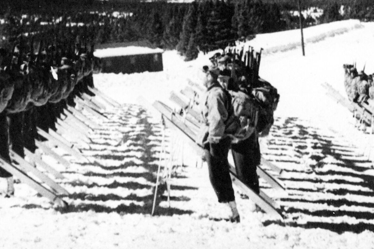 The image depicts soldiers marching in snow, with some moving on railroad tracks, showcasing a winter military scene.